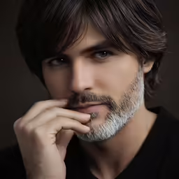 a man is wearing a black shirt and his hand is near his face