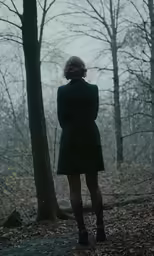 the young woman is looking at the trees in the woods