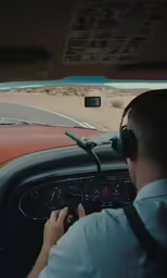man driving in a small car in a desert