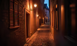 a narrow street lined with brick buildings at night