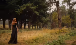 a woman in black dress standing in a forest