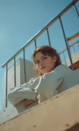 a woman in a white shirt sitting on a metal balcony