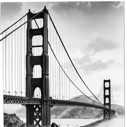 a black and white photo of a long bridge over a bay