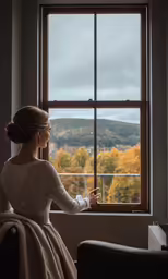the young woman is looking out the window of the mountain view