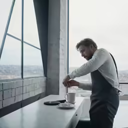 a man is sitting at the table and having a cup of coffee
