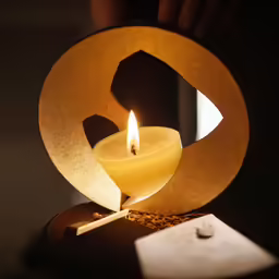 a lighted candle in the shape of a circle on top of a coaster