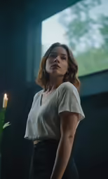 a woman in a white top and black pants looks to the side