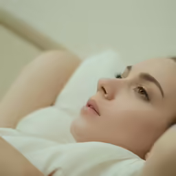 a beautiful young lady laying on a bed with her head propped on one end