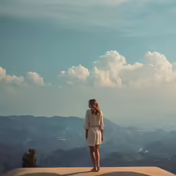 woman wearing dress looking at sky from mountain