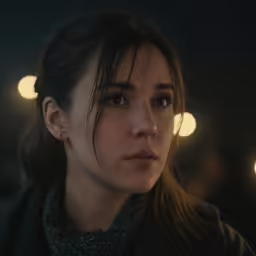 a woman in a dark room looking away from the camera