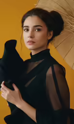 woman in black with umbrella poses for the camera