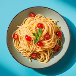 an overhead view of noodles with tomatoes and basil