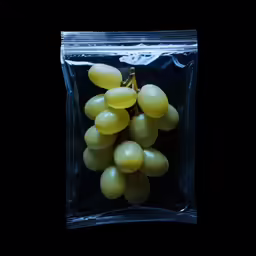 grapes sitting inside of a package on top of a black surface