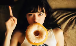 a woman holding a donut with her finger up