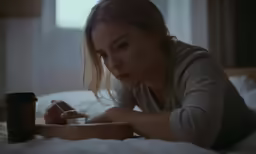 a woman laying on a bed with a drink