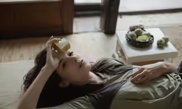 a woman sitting on the floor while holding a juice bottle