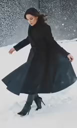woman in the snow walking uphill in a black coat