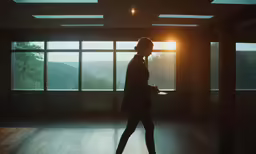 a woman walking into a dark room with a window and some sunlight