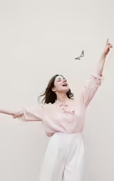 an attractive woman in white pants flying a kite