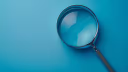 a magnifying glass on a blue background,the blue background has a round looking glass on it