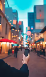 the person holds a smart phone over an urban street