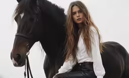 a young girl posing for a picture next to a black horse