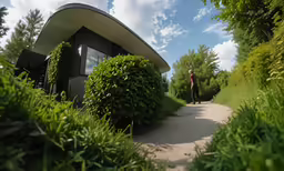 a bike rider rides alongside a curving curve of hedges