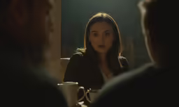 the woman is sitting in the room looking into the distance