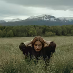 a woman in a field with mountains behind her