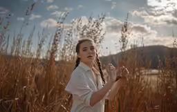 woman in a field with braids, posing in a pose