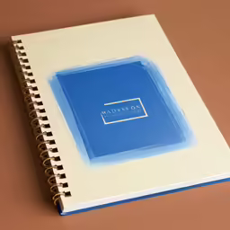 a white and blue notebook on brown table