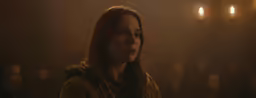 an elegant woman staring directly in the dark with others behind her
