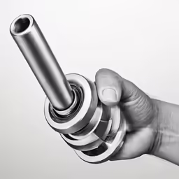 a hand holding a metal object on top of a white surface