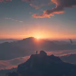 two people at the peak overlooking the mountains during a beautiful sunset