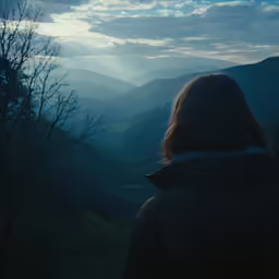 the back end of a woman looking at the hills