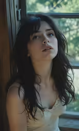 a woman in a white shirt posing by a window