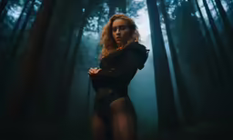 a woman standing in the woods with her arms crossed