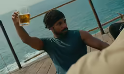 a man with a beard is holding up a glass of beer