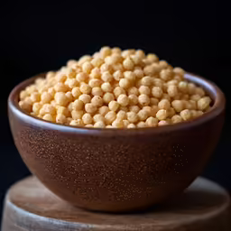 a wooden bowl filled with chick peas on top of a wooden counter