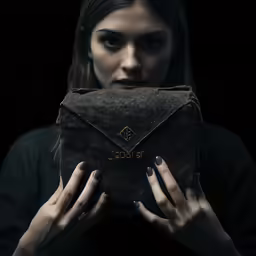 a woman hides her face behind an old briefcase
