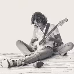 a person playing guitar sitting on the ground