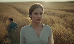 two people walk through a field with tall grass