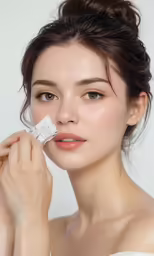 a beautiful woman is putting a white cream on her face