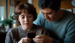 a man and woman sitting together using a cell phone