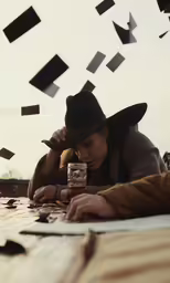 a woman with a hat is on her phone while looking at her electronic device