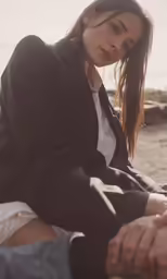 a woman in a black jacket is sitting down