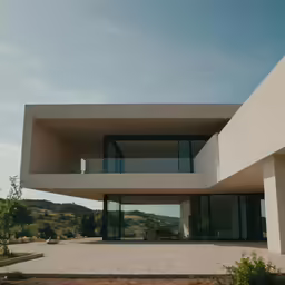 a building sitting on top of a dirt road next to a hillside