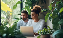 two people sitting at a desk on their laptop