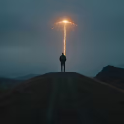 a man standing in the middle of a field with a light that is shining