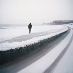 a man walking on top of a snow covered field